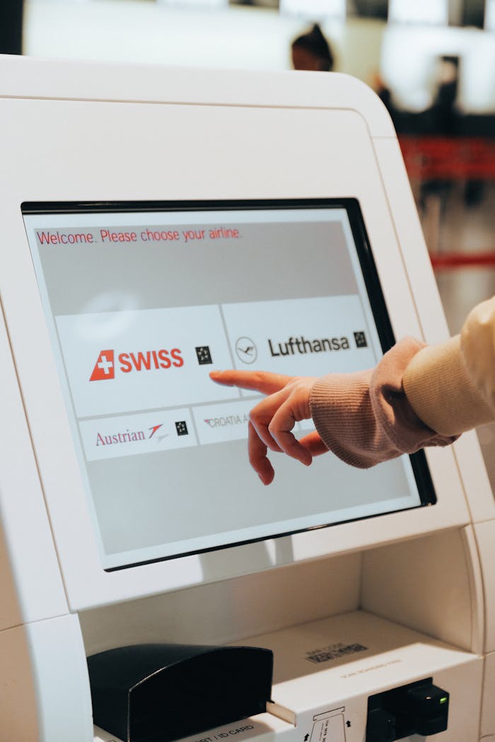 Hand interacting with airport kiosk for airline selection. Modern travel technology.